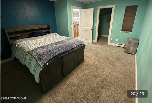 bedroom with a closet, light colored carpet, baseboard heating, and a spacious closet