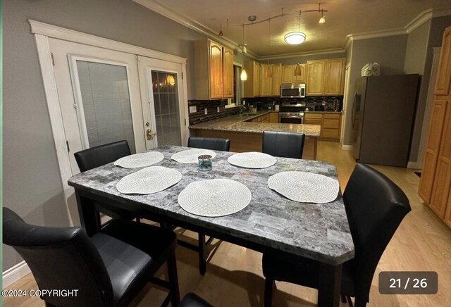 kitchen featuring appliances with stainless steel finishes, crown molding, sink, decorative backsplash, and light wood-type flooring