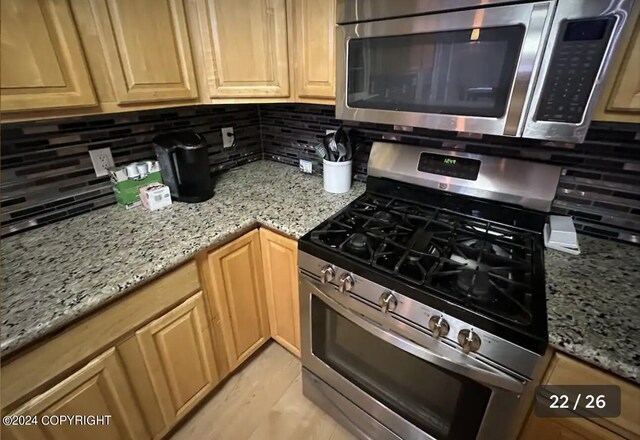 kitchen featuring appliances with stainless steel finishes, light stone counters, and decorative backsplash