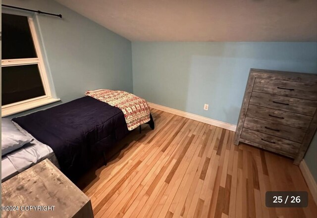 bedroom with vaulted ceiling and light hardwood / wood-style flooring