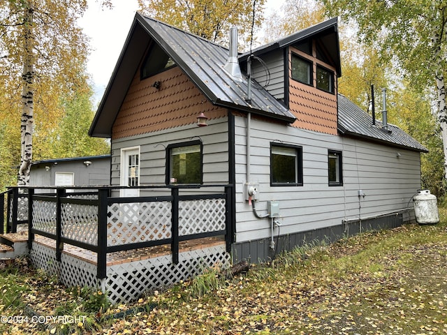 back of house with metal roof and a deck