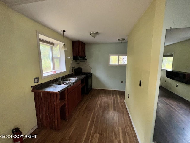 kitchen featuring black gas range oven, dark countertops, a wealth of natural light, and a sink