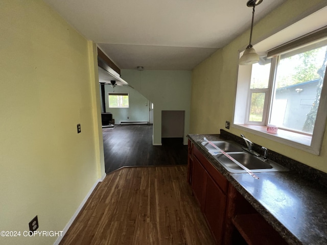 kitchen featuring dark countertops, plenty of natural light, dark wood finished floors, and a sink