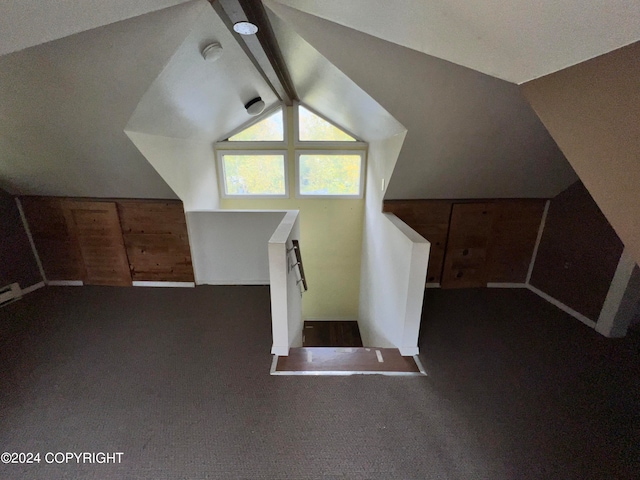 additional living space featuring dark carpet and lofted ceiling with beams