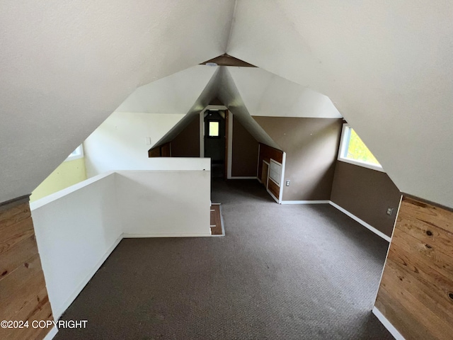 additional living space featuring lofted ceiling and dark colored carpet