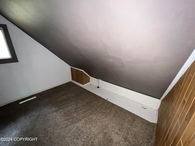 bonus room featuring lofted ceiling, wood walls, and carpet flooring