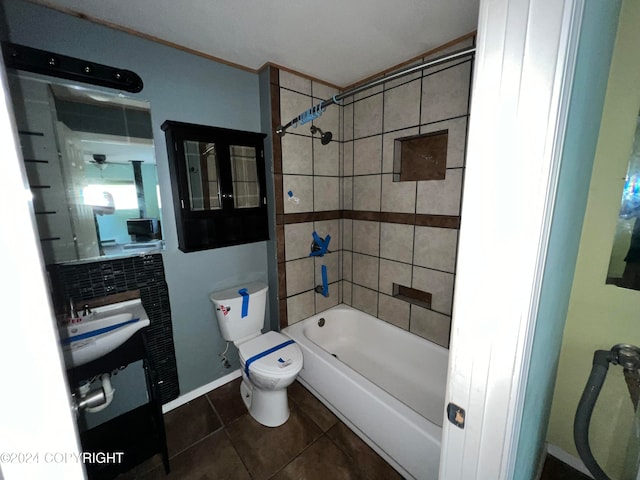 bathroom featuring tiled shower / bath, toilet, and tile patterned flooring