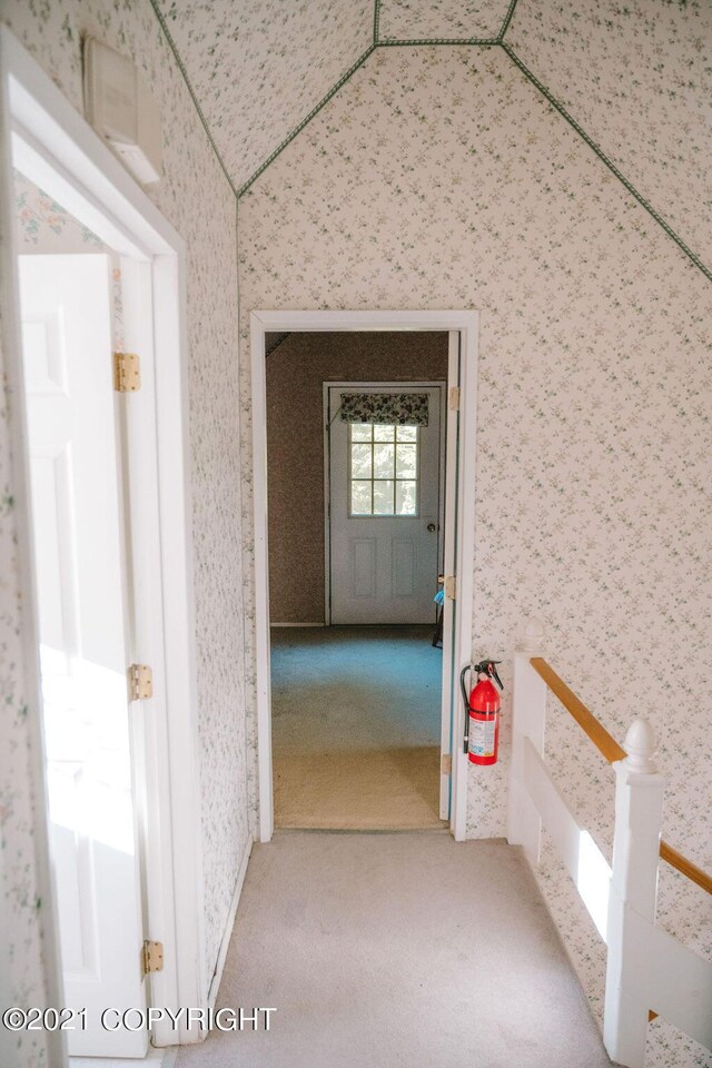 corridor with lofted ceiling, carpet flooring, and a wealth of natural light