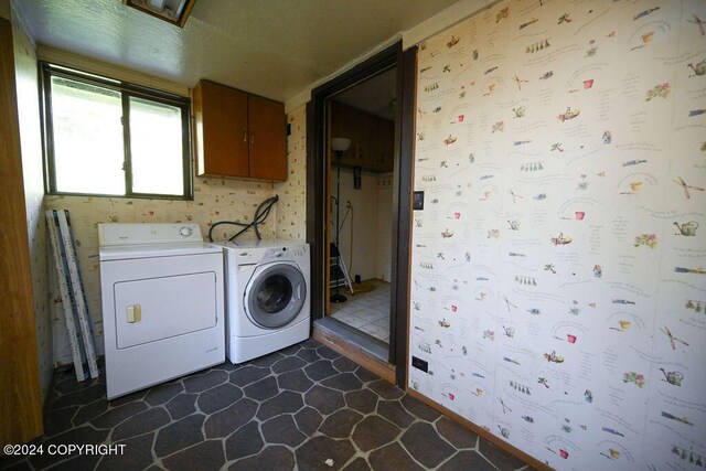 laundry area featuring cabinets, washing machine and dryer, and dark tile patterned flooring