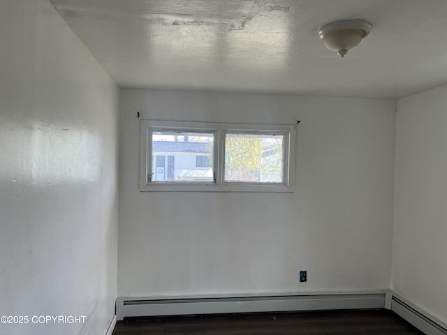 empty room featuring baseboard heating and wood finished floors