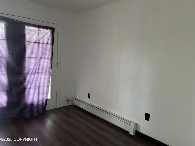 spare room with a baseboard radiator, healthy amount of natural light, and dark wood-type flooring