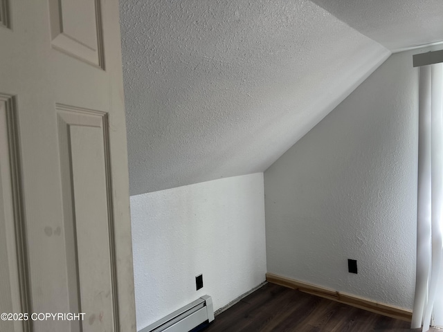 additional living space featuring a textured ceiling, vaulted ceiling, dark wood-style floors, baseboards, and a baseboard heating unit