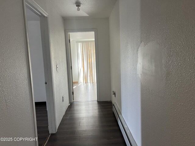 hallway featuring a textured wall, a baseboard radiator, and dark wood finished floors