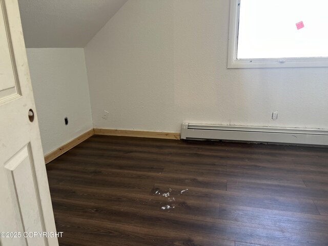 additional living space featuring baseboard heating, dark wood-type flooring, and baseboards