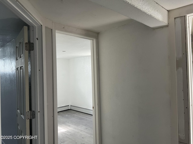 corridor with a baseboard radiator and wood finished floors