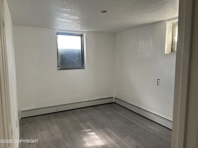 empty room with a textured ceiling, wood finished floors, and a textured wall
