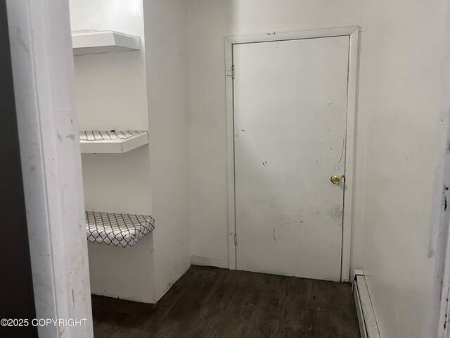 doorway with dark wood-style flooring and baseboard heating