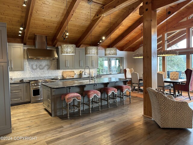 345 C St, Seldovia, AK 99663 - kitchen with gray cabinets, a sink, a breakfast bar, wall chimney range hood, and stainless steel stove