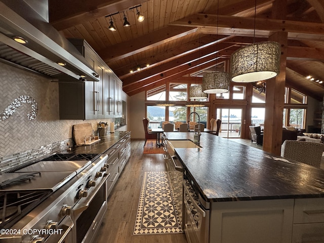 345 C St, Seldovia, AK 99663 - kitchen with high end stainless steel range, a sink, a center island with sink, dark wood finished floors, and wall chimney range hood