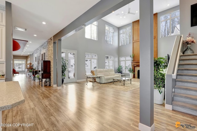 8100 Sky Mountain Ln, Anchorage, AK 99502 - living room featuring stairway, healthy amount of natural light, light wood-style flooring, a high ceiling, and a fireplace