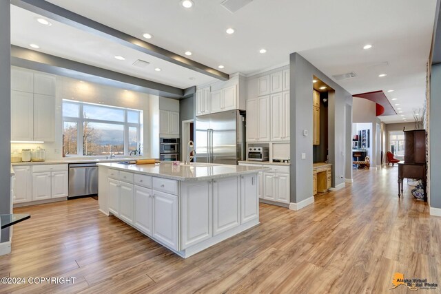 8100 Sky Mountain Ln, Anchorage, AK 99502 - kitchen featuring stainless steel appliances, light wood-type flooring, white cabinets, a center island with sink, and recessed lighting