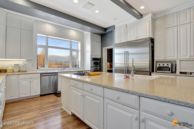 8100 Sky Mountain Ln, Anchorage, AK 99502 - kitchen featuring stainless steel appliances, a sink, white cabinetry, light stone countertops, and light wood-style flooring