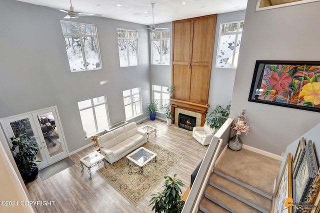 8100 Sky Mountain Ln, Anchorage, AK 99502 - living room featuring a ceiling fan, plenty of natural light, a tiled fireplace, wood finished floors, and a high ceiling