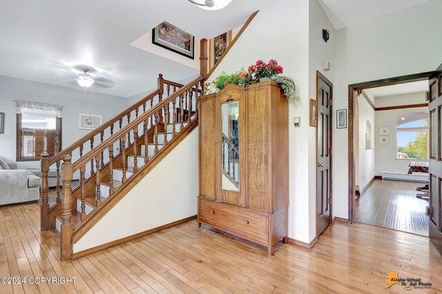 stairway with ceiling fan, hardwood / wood-style floors, and a healthy amount of sunlight