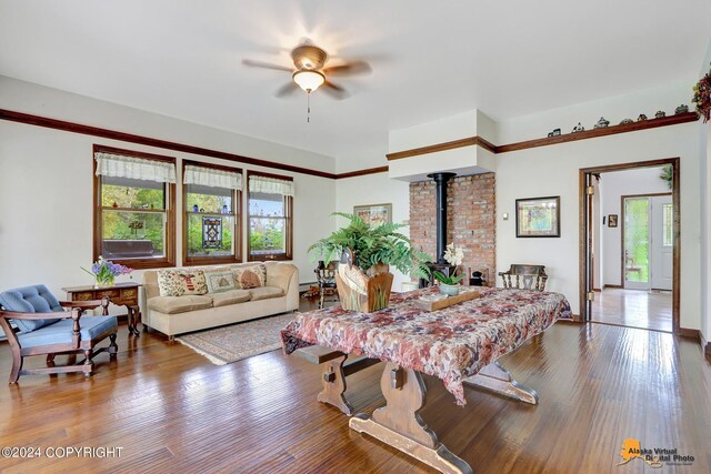 living room with ceiling fan, hardwood / wood-style flooring, and a wood stove