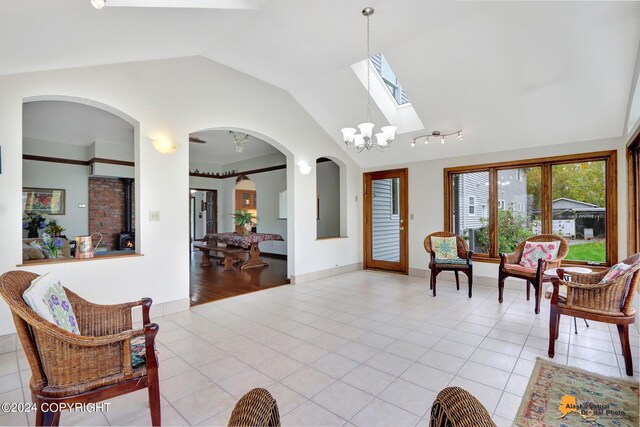 living room featuring light wood-type flooring, a chandelier, and lofted ceiling with skylight