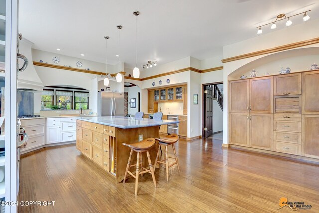 kitchen featuring appliances with stainless steel finishes, white cabinets, a kitchen island, a breakfast bar area, and decorative light fixtures