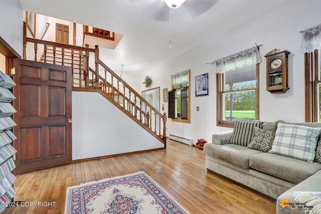 living room featuring ceiling fan, baseboard heating, and light hardwood / wood-style floors