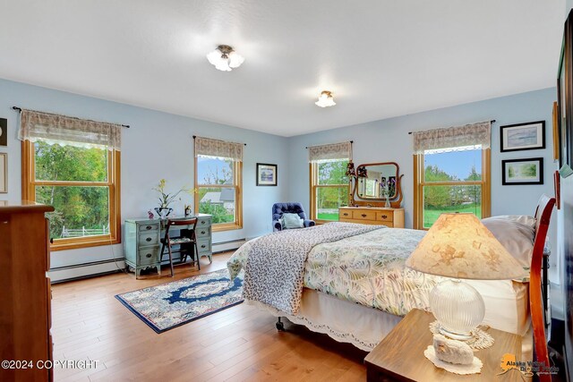 bedroom with a baseboard radiator, multiple windows, and hardwood / wood-style flooring