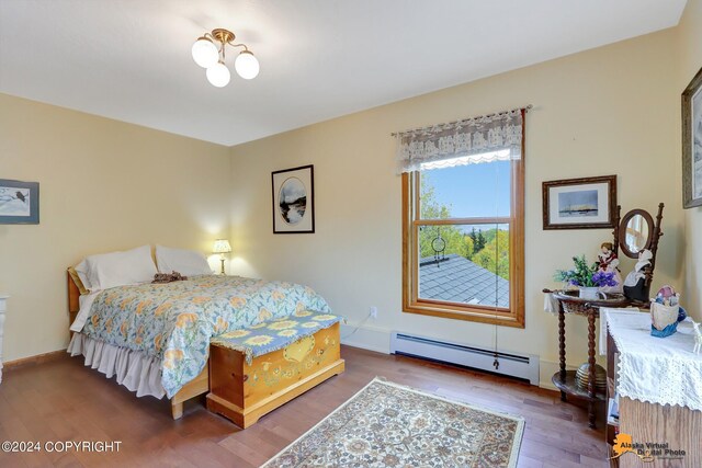 bedroom featuring dark wood-type flooring and a baseboard heating unit