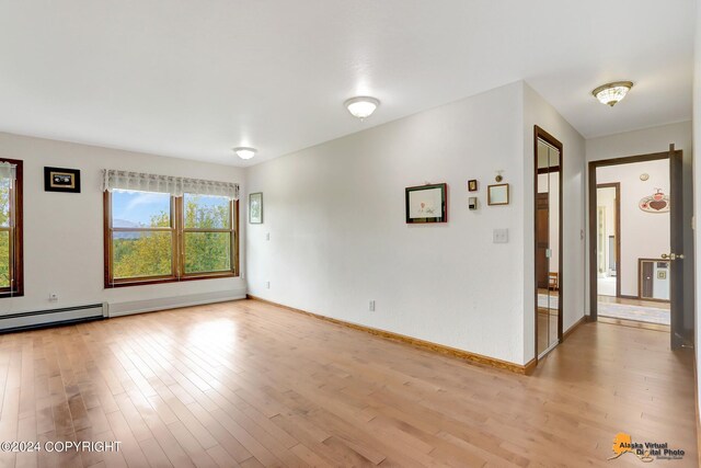 unfurnished room featuring light wood-type flooring and baseboard heating