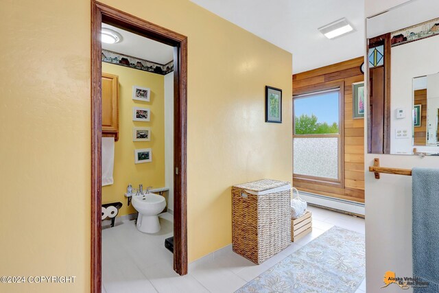 hall featuring a baseboard radiator, wood walls, and light tile patterned floors
