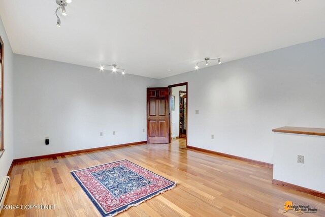 empty room featuring a baseboard radiator and light hardwood / wood-style flooring