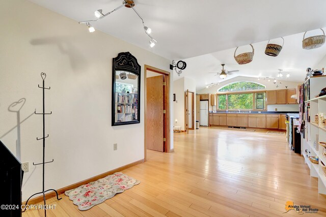 foyer featuring light wood-type flooring, vaulted ceiling, and ceiling fan