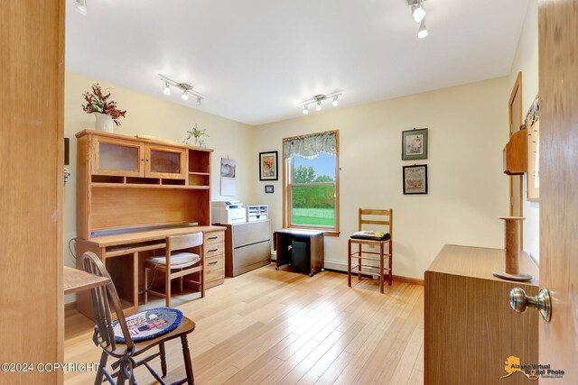 office with light hardwood / wood-style floors and rail lighting
