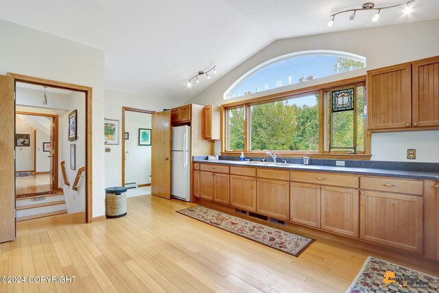 kitchen with lofted ceiling, light hardwood / wood-style floors, white fridge, and sink