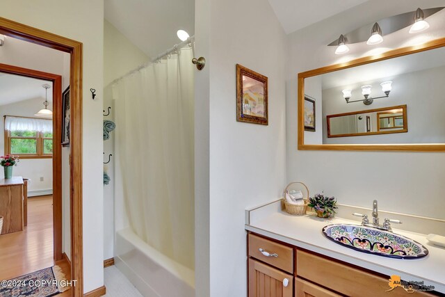 bathroom with vaulted ceiling, baseboard heating, hardwood / wood-style floors, shower / bath combo with shower curtain, and vanity