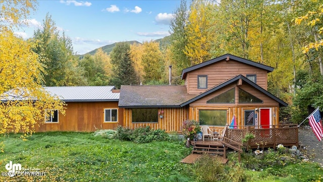 rear view of house featuring a lawn and a deck