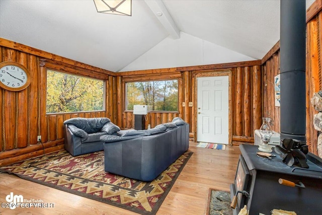 living room with vaulted ceiling with beams, a wood stove, hardwood / wood-style floors, and a healthy amount of sunlight