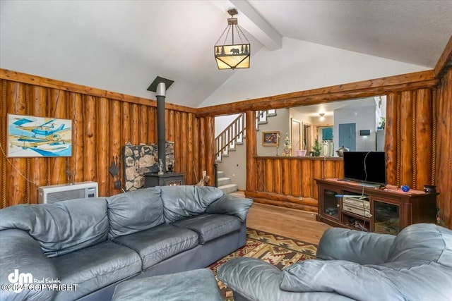 living room with wood walls, lofted ceiling with beams, a wood stove, and hardwood / wood-style flooring