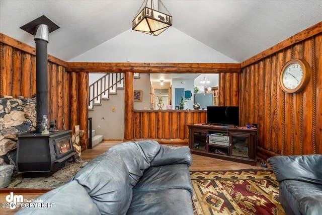 living room featuring light hardwood / wood-style flooring, a wood stove, and lofted ceiling