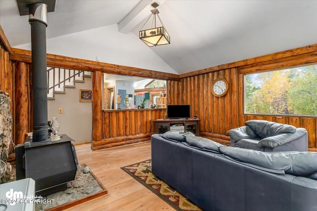 living room with wood-type flooring, lofted ceiling with beams, wood walls, and a wood stove