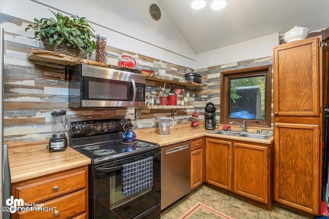 kitchen with vaulted ceiling, stainless steel appliances, sink, and decorative backsplash