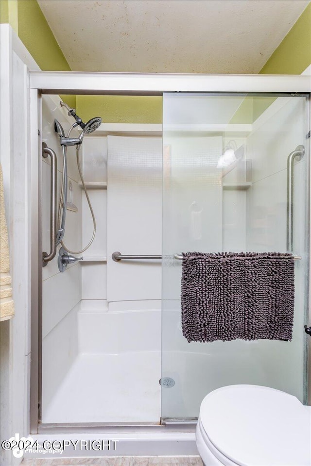 bathroom with toilet and an enclosed shower