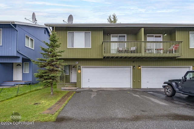 view of front facade with a balcony, a garage, and a front yard