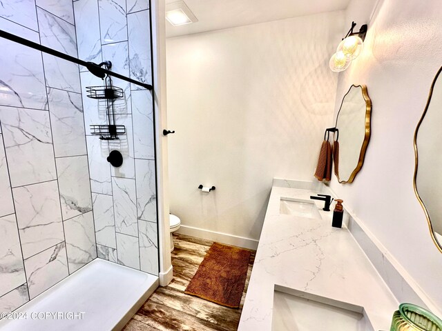 bathroom featuring a tile shower, vanity, hardwood / wood-style flooring, and toilet